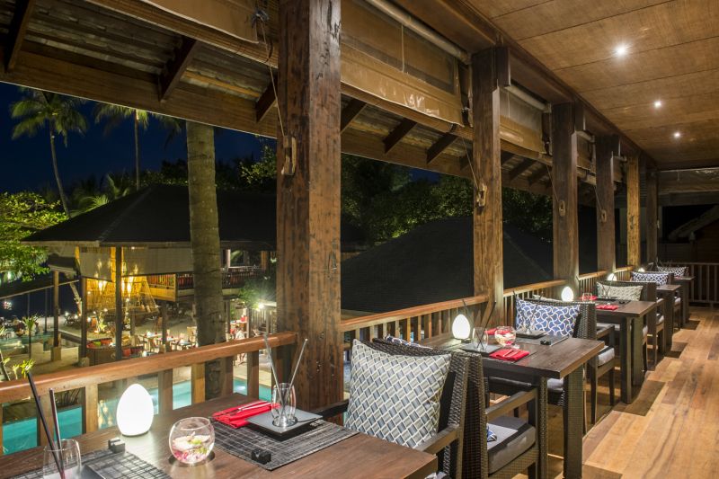 Yukinoya Restaurant Terrasse eines gehobenen Restaurants bei Abenddämmerung mit stilvoller Beleuchtung, Blick auf einen beleuchteten Poolbereich und tropische Vegetation im Hintergrund. Die Tische sind elegant gedeckt, mit spezifischem Fokus auf Textilien und Geschirr, die eine einladende Atmosphäre schaffen.