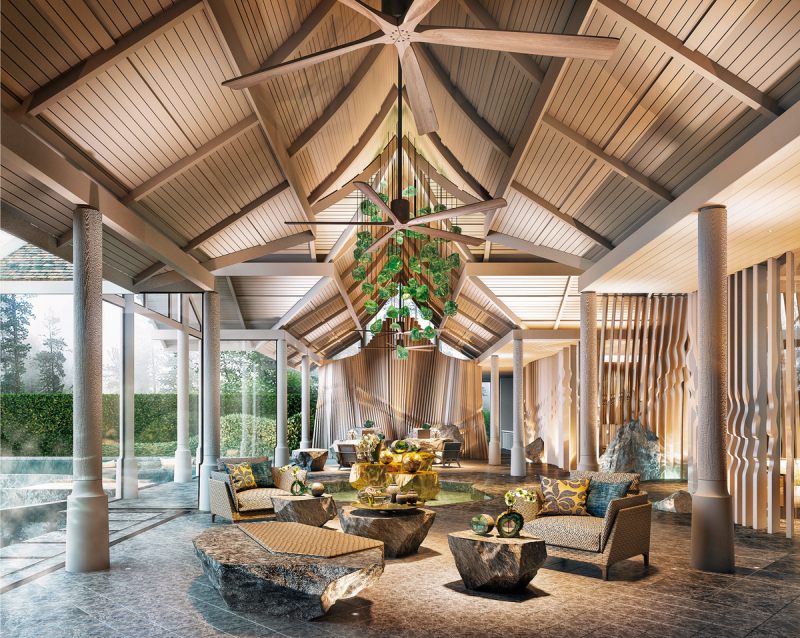 Lounge Innenraum eines luxuriösen Lounge-Bereichs mit hohen Decken und Holzbalken. Ein großer Deckenventilator hängt über einem zentral angeordneten Sitzbereich mit gemusterten Sofas und unregelmäßig geformten Holztischen. Der Raum verfügt über bodentiefe Fenster mit Blick ins Grüne, dekorative Pflanzen und skulpturale Lichtinstallationen, die für eine warme Atmosphäre sorgen.