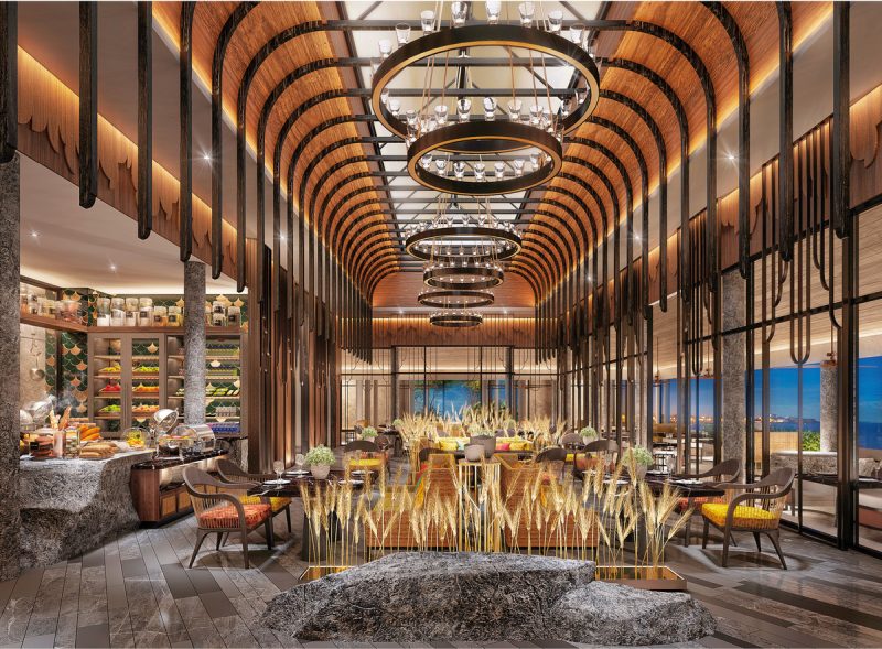 Restaurant Ein luxuriös gestaltetes Restaurant mit modernen Holzelementen und eleganten Beleuchtungseinrichtungen. Steintheke mit einer Auswahl an kulinarischen Angeboten links im Bild, stilvolle Sitzgelegenheiten im Vordergrund und Panoramafenster mit Meerblick im Hintergrund.