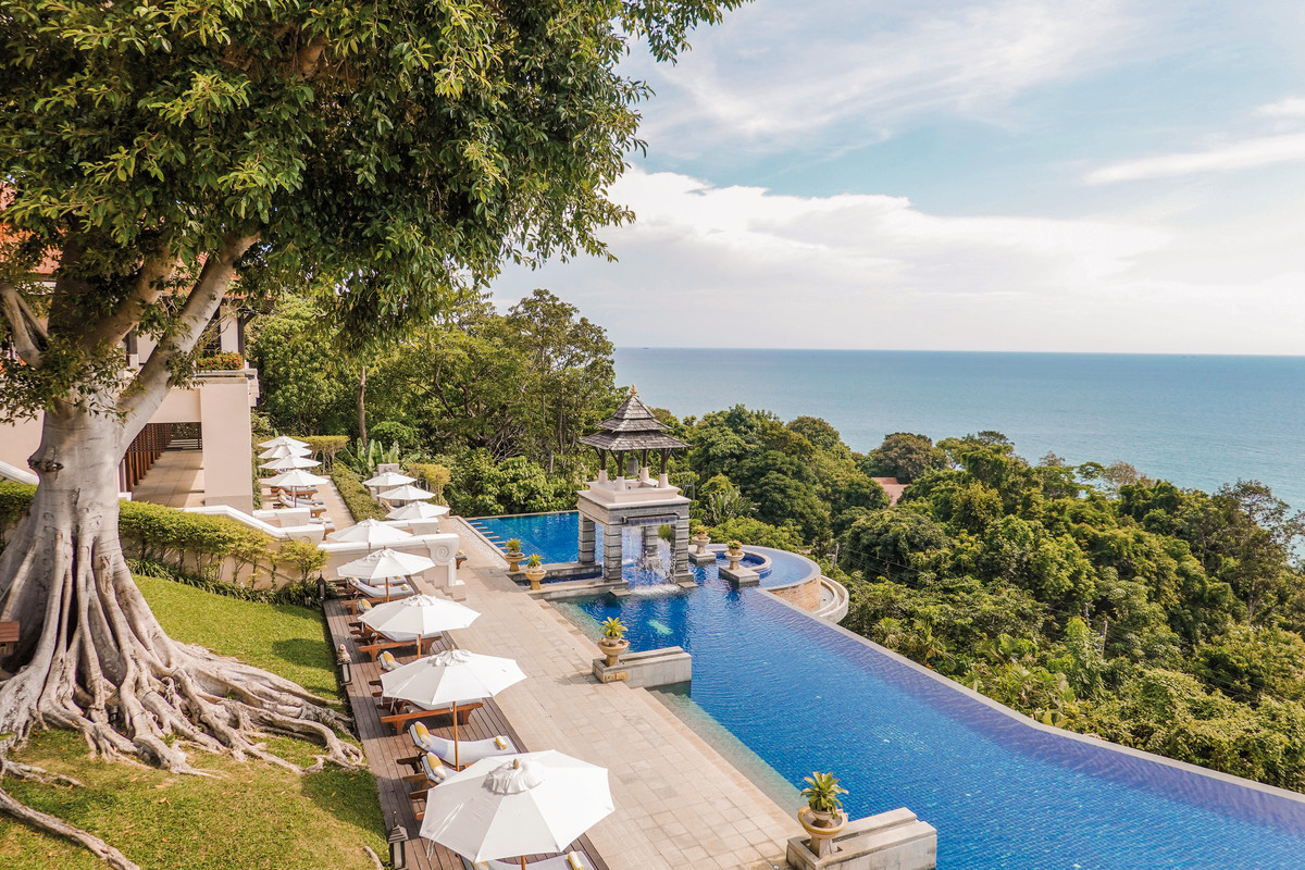Pool Ein luxuriöser Infinity-Pool mit Blick auf das Meer, umgeben von einem üppigen Waldgebiet. Weiße Sonnenschirme und Liegestühle stehen auf der Terrasse bereit für Entspannung. Eine traditionelle Pavillon-Struktur befindet sich am Ende des Pools.
