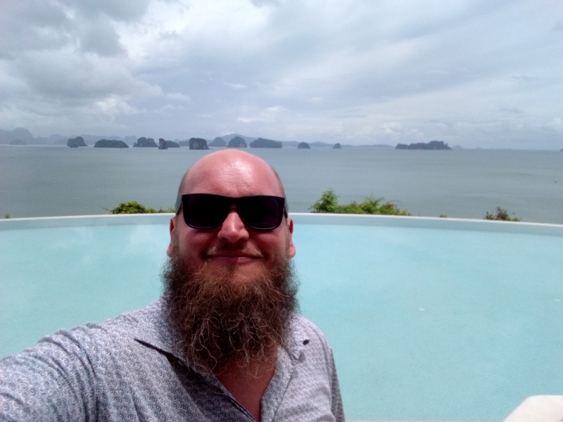 Pool mit atemberaubenden Blick im Six Senses Yao Noi – 0x0040 Ein Mann mit Bart und Sonnenbrille macht ein Selfie vor einem Infinity-Pool, der den Blick auf eine malerische Meereslandschaft mit Inseln im Hintergrund freigibt.