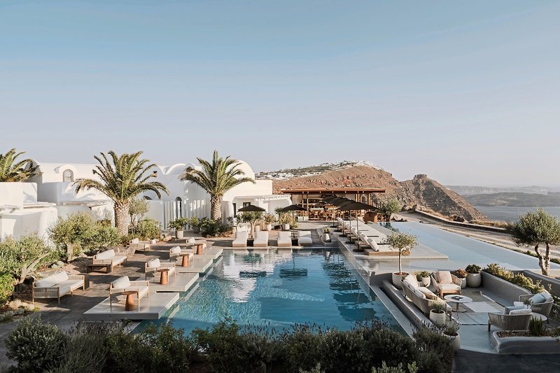 Pool Ein luxuriöses Resort mit Poolbereich in minimalistischem Design, flankiert von weißen Gebäuden und Palmen, mit einer atemberaubenden Aussicht auf eine hügelige Landschaft im Hintergrund.